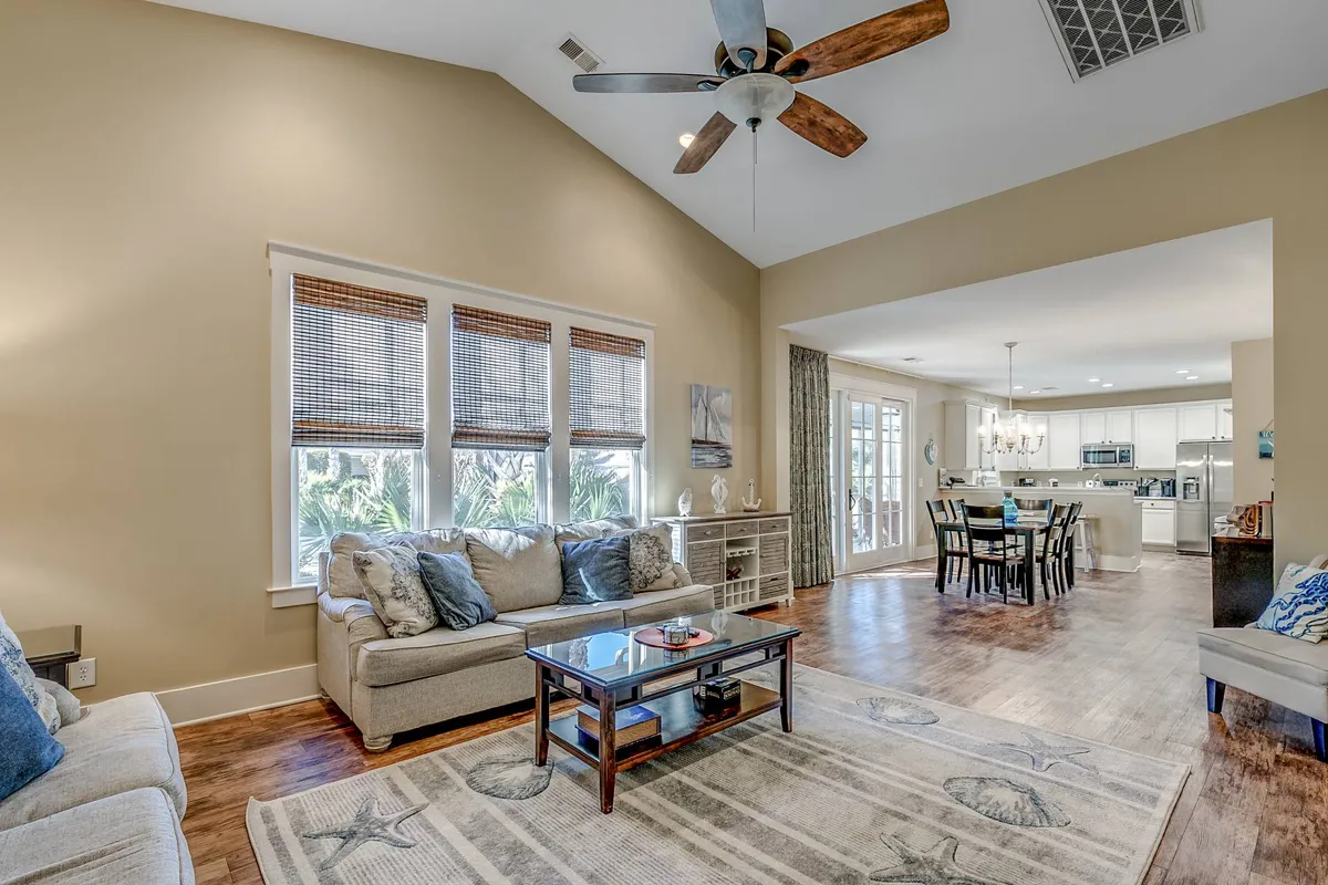 An inviting open living space featuring a plush sofa set and a coffee table, seamlessly connected to a dining area. Large windows let in abundant natural light, creating a warm atmosphere perfect for family gatherings, relaxed conversations, and entertaining guests.