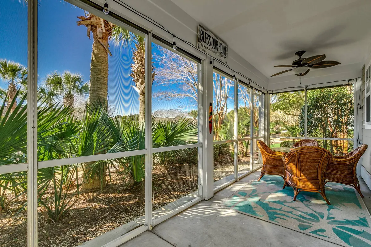 This image features a serene seating area with woven chairs, a decorative rug, potted plants, and a view through the window to the outdoors. The inviting space encourages relaxation and socializing, with natural elements that suggest a connection to leisure and wellness activities.