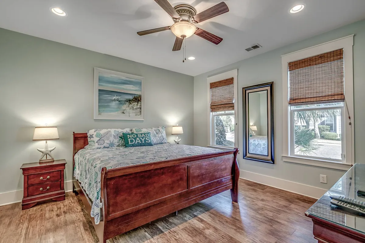 A tranquil master bedroom featuring a plush bed with elegant linens, complemented by tasteful artwork and mirrors above the nightstands. Soft lighting and a serene atmosphere make this space inviting for rest and relaxation.