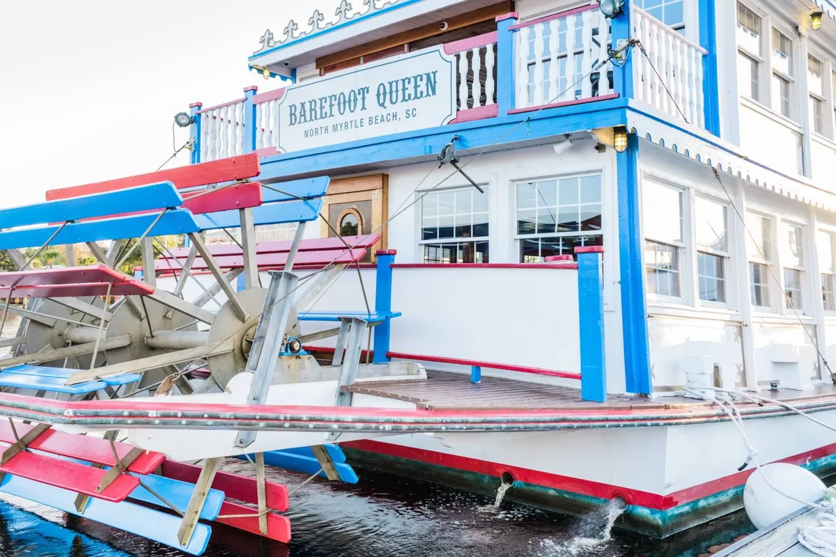 An exterior shot of a cheerful paddlewheel cruise boat with a colorful facade and clear signage. The image evokes feelings of adventure, social gatherings, and themed experiences on the water.