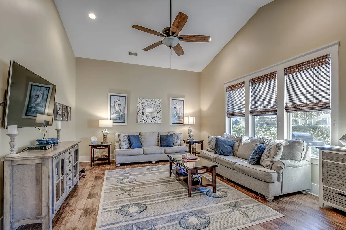 A spacious living room featuring plush sofa sets, tasteful wall art, and a central coffee table. Natural light fills the space, creating an inviting atmosphere ideal for social gatherings or relaxing with family after a day of exploring Myrtle Beach attractions.